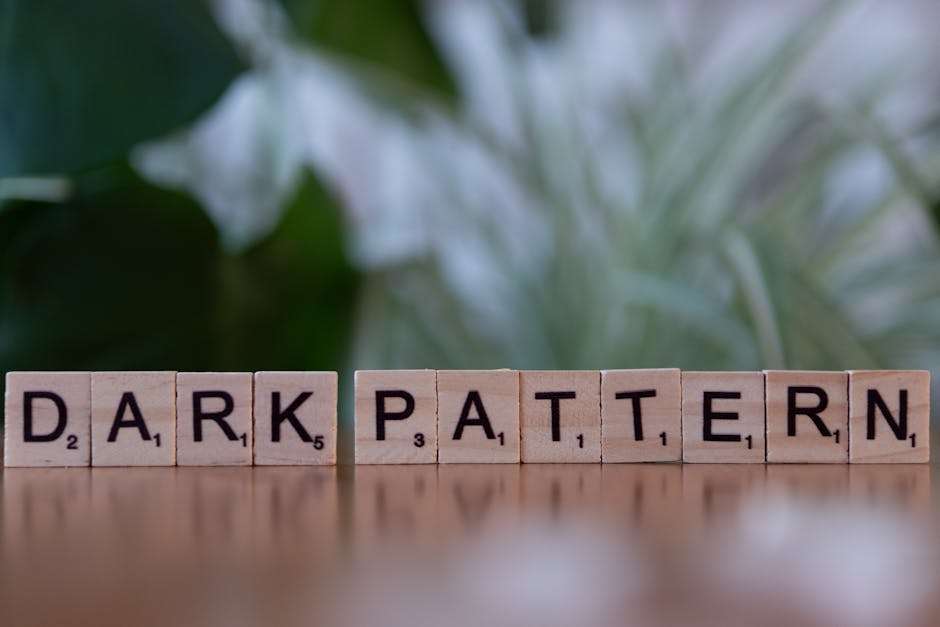 Drewniane klocki z literami tworzące napis „DARK PATTERN” ustawione na drewnianym blacie.