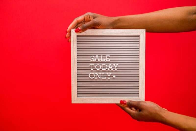 kobieta trzymająca w rękach tabliczkę z napisem "SALE TODAY ONLY" na jaskrawo czerwonym tle