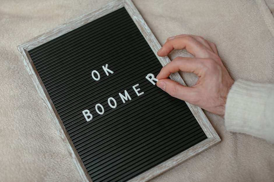 Ręka umieszczająca literę „R” na tablicy z napisem „OK BOOMER”.