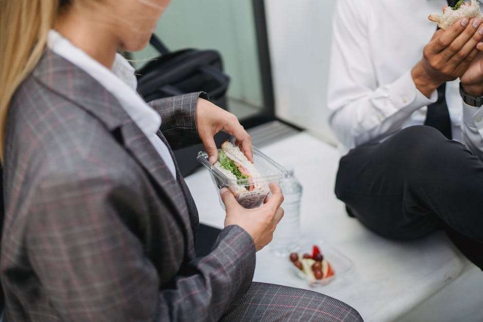 Kobieta i mężczyzna w strojach biznesowych jedzą kanapki podczas przerwy na lunch.
