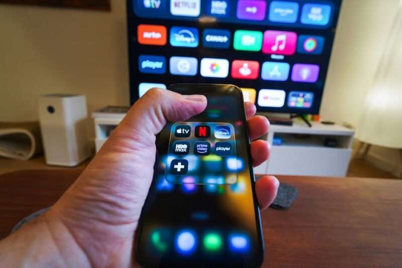 smartfon w ręku na tle telewizora