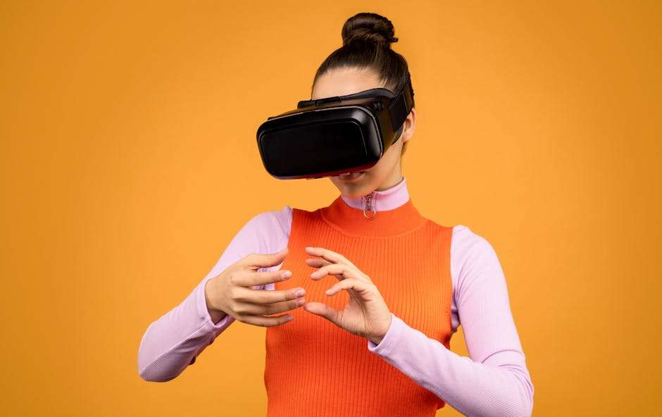 Kobieta w goglach VR wykonuje gesty dłońmi na tle żółtej ściany.